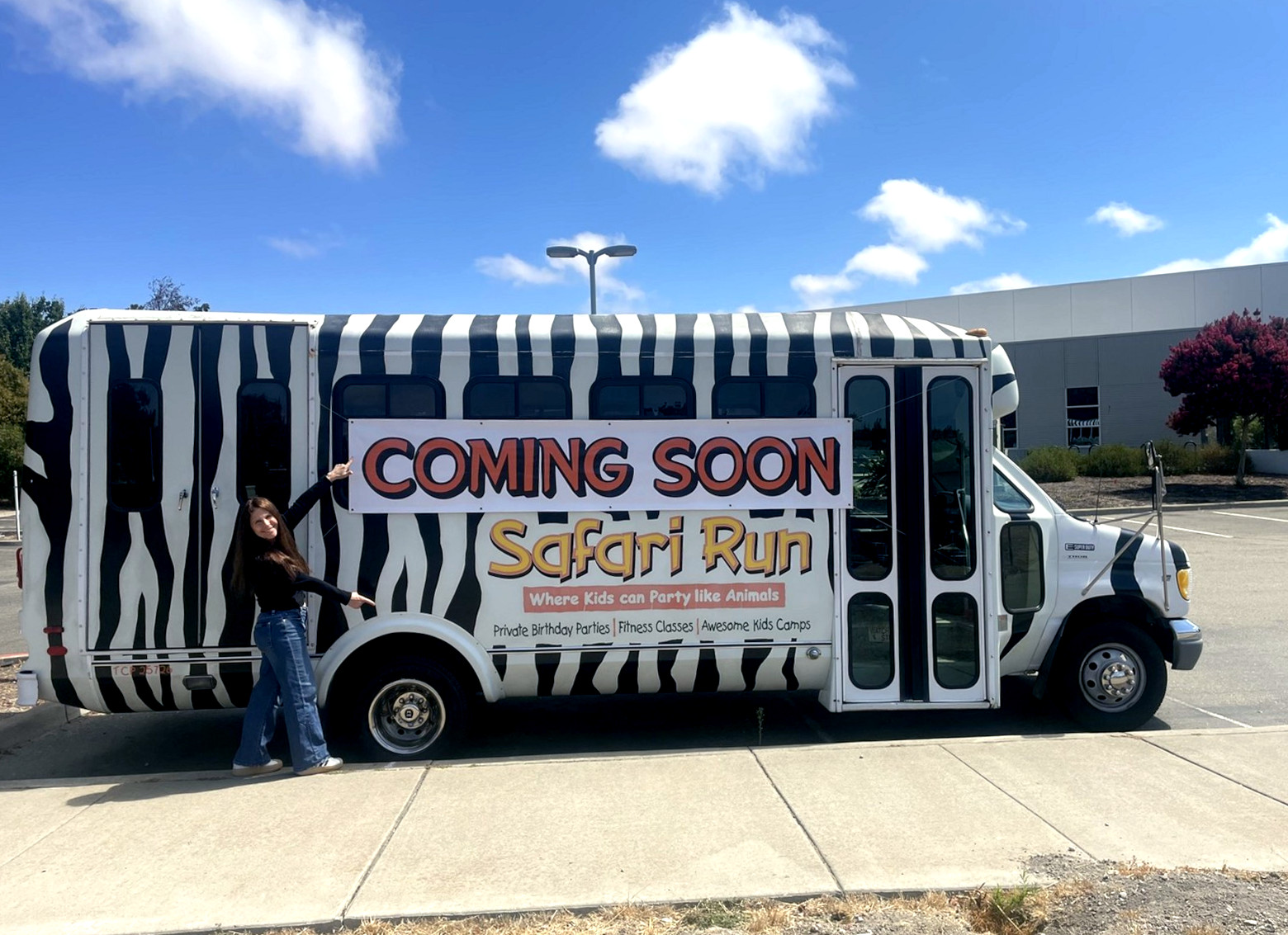 The Safari Run zebra-striped bus parked outside the Livermore site, with a Coming Soon banner along its side